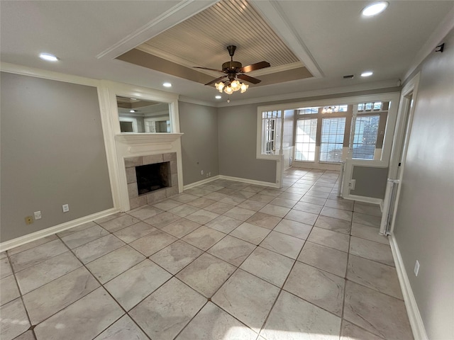 unfurnished living room featuring a raised ceiling, a fireplace, crown molding, and baseboards