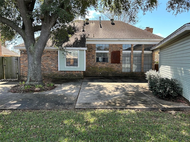 rear view of house featuring brick siding, a patio area, and a shingled roof