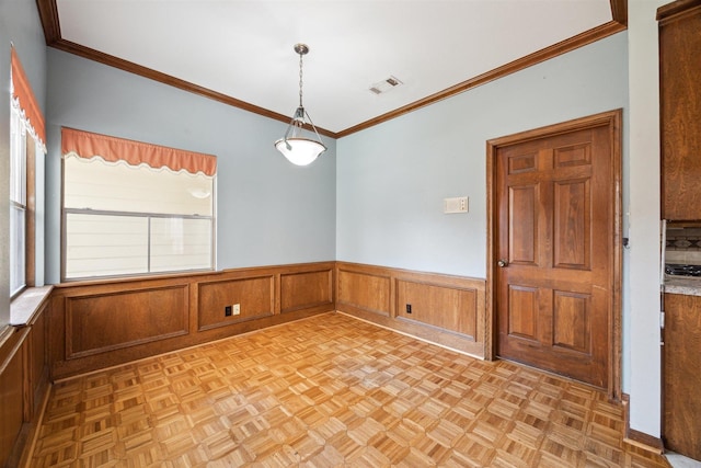 spare room with a wainscoted wall, visible vents, and crown molding