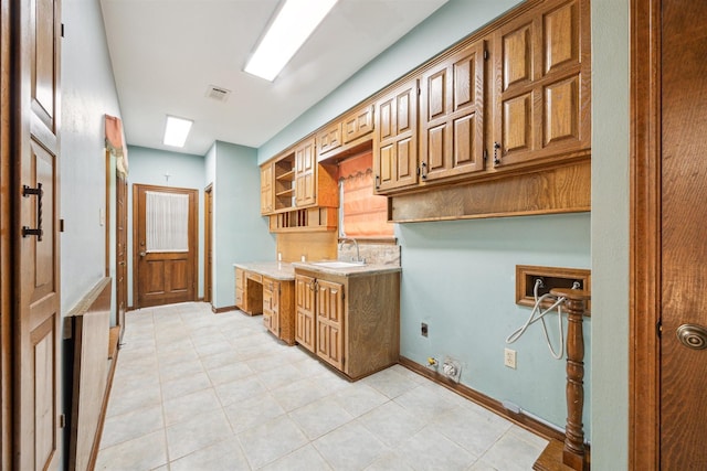 kitchen with baseboards, visible vents, brown cabinets, light countertops, and a sink