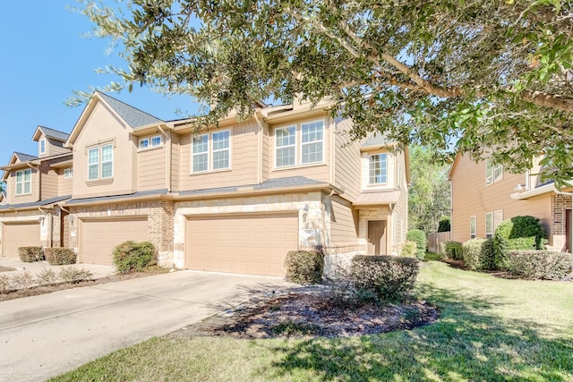 multi unit property with a garage, concrete driveway, stone siding, and a front yard