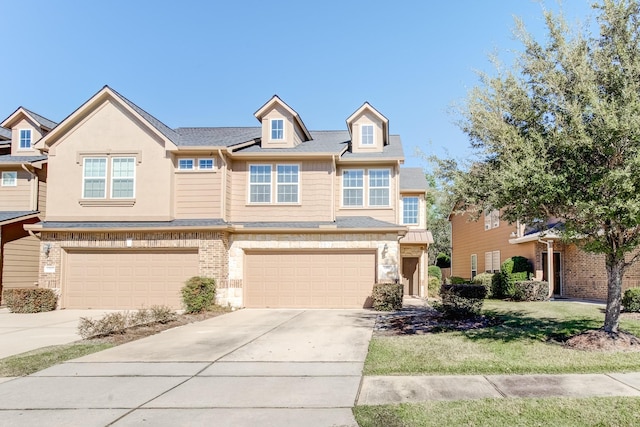 multi unit property featuring a garage, driveway, and brick siding