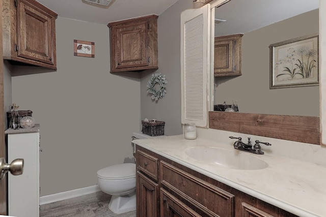 half bath with visible vents, vanity, toilet, and baseboards