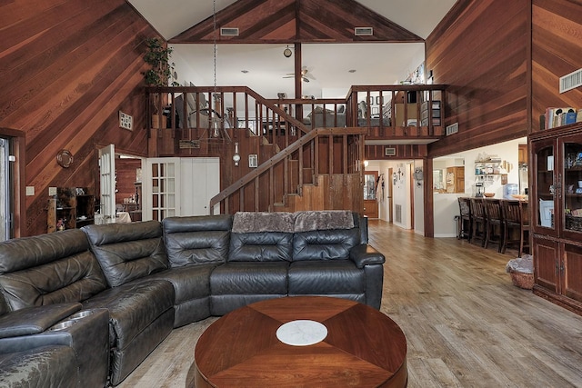 living area featuring wood walls, stairway, and light wood-style floors