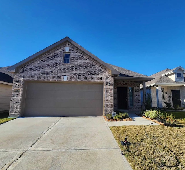 view of front of home with an attached garage, driveway, and brick siding