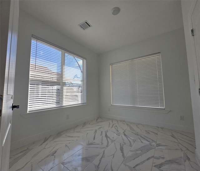 spare room with marble finish floor, visible vents, and baseboards