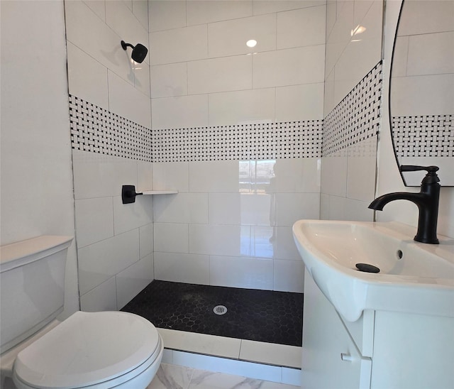 full bathroom with vanity, a tile shower, and toilet