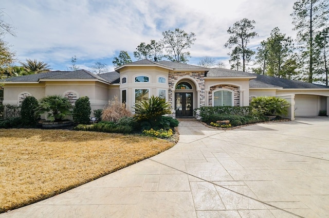 view of front of house featuring a garage, french doors, concrete driveway, and stucco siding