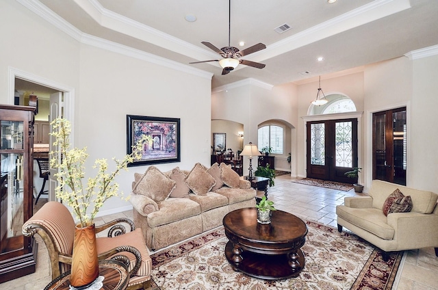 living room with arched walkways, stone tile floors, visible vents, french doors, and a tray ceiling