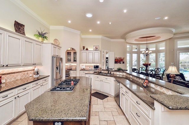 kitchen with appliances with stainless steel finishes, a sink, a large island, and crown molding