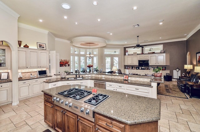 kitchen featuring a spacious island, a sink, appliances with stainless steel finishes, stone tile flooring, and crown molding