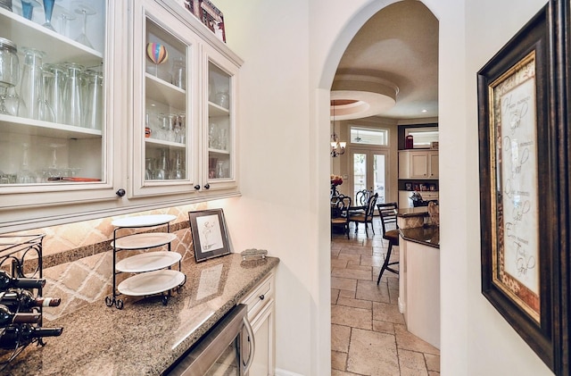 bar featuring arched walkways, stone tile flooring, decorative backsplash, and wine cooler