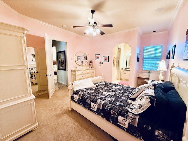 bedroom featuring light carpet, arched walkways, a ceiling fan, ensuite bath, and ornamental molding