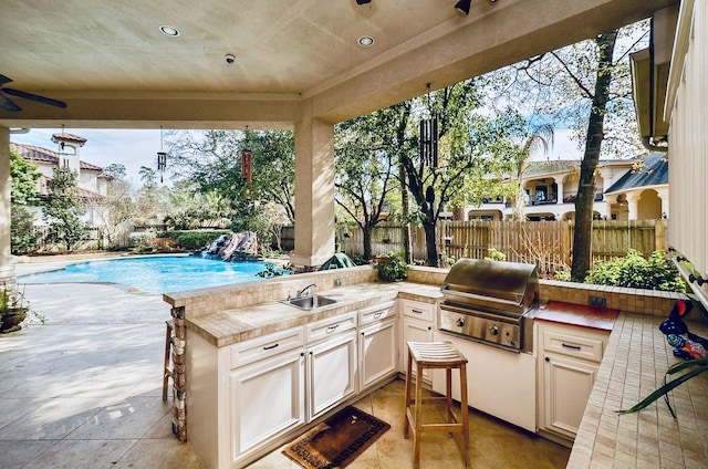 view of patio with a fenced in pool, an outdoor kitchen, a sink, a grill, and fence private yard