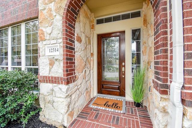 doorway to property featuring stone siding and brick siding