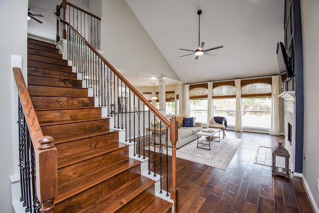 living room featuring a fireplace, decorative columns, stairway, a ceiling fan, and wood finished floors