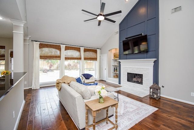 living room featuring visible vents, dark wood finished floors, baseboards, a fireplace with flush hearth, and built in shelves