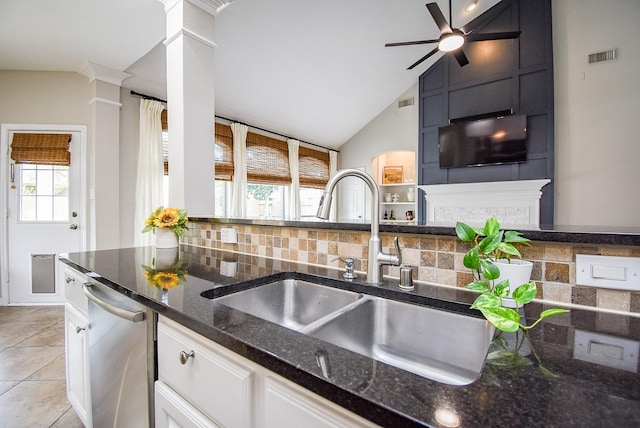 kitchen with a sink, white cabinetry, stainless steel dishwasher, dark stone counters, and tasteful backsplash