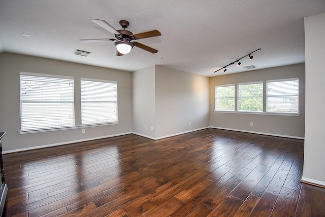 spare room with ceiling fan, visible vents, dark wood finished floors, and baseboards