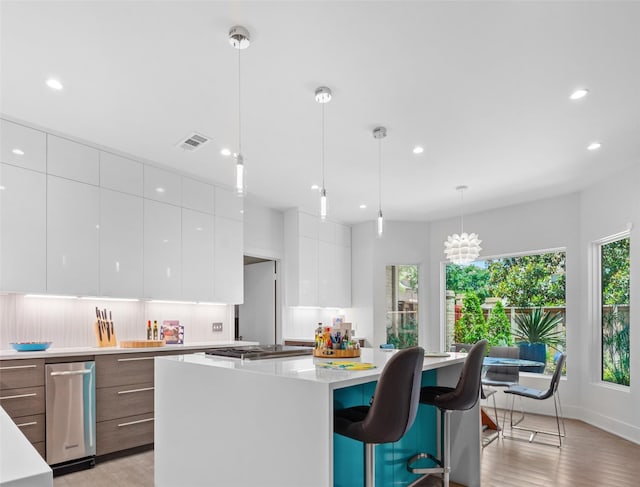 kitchen featuring white cabinets, a kitchen island, modern cabinets, light countertops, and pendant lighting