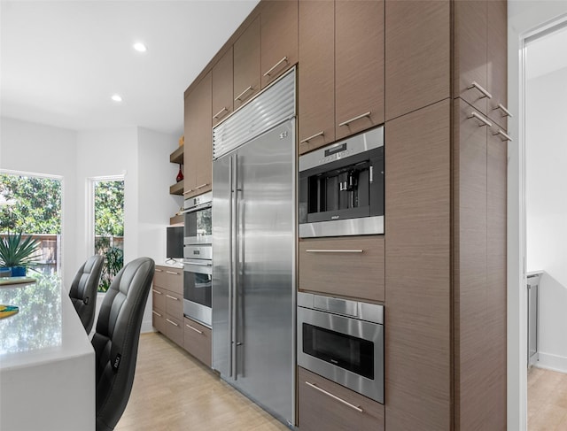 kitchen featuring open shelves, recessed lighting, modern cabinets, light wood-type flooring, and built in appliances