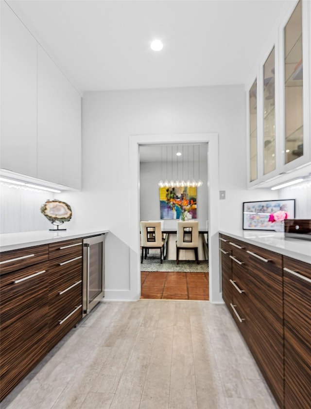 kitchen with light countertops, wine cooler, glass insert cabinets, and white cabinets