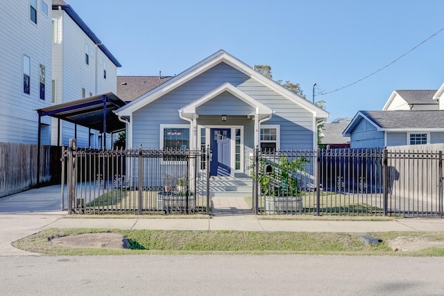 bungalow-style home featuring driveway, a fenced front yard, and a gate