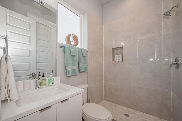 full bathroom featuring tiled shower, vanity, and toilet