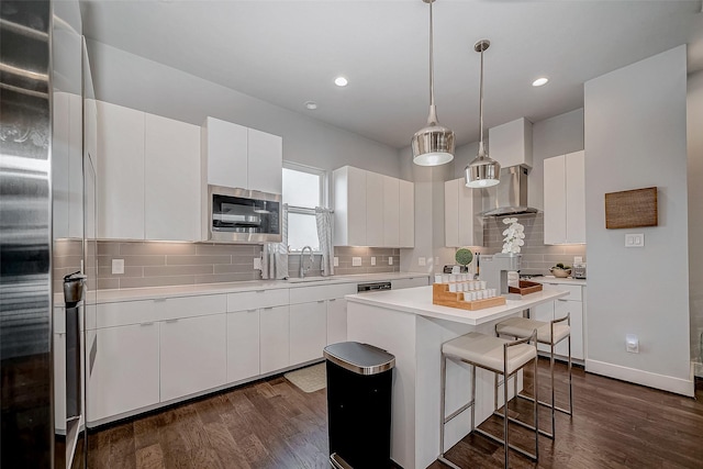 kitchen with light countertops, wall chimney range hood, and white cabinetry