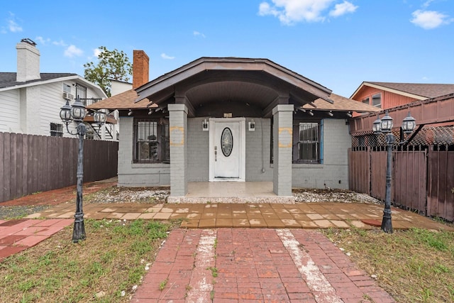 bungalow featuring a fenced front yard and brick siding