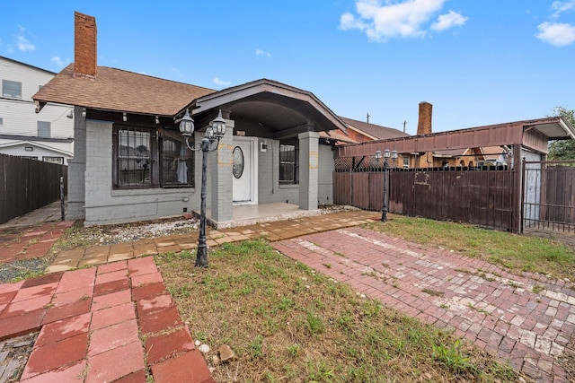 view of front of house with a fenced front yard, a chimney, and roof with shingles