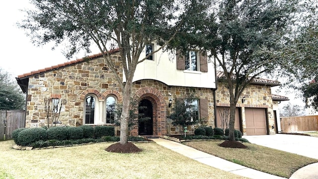 view of front of property with concrete driveway, a front yard, fence, a garage, and stone siding