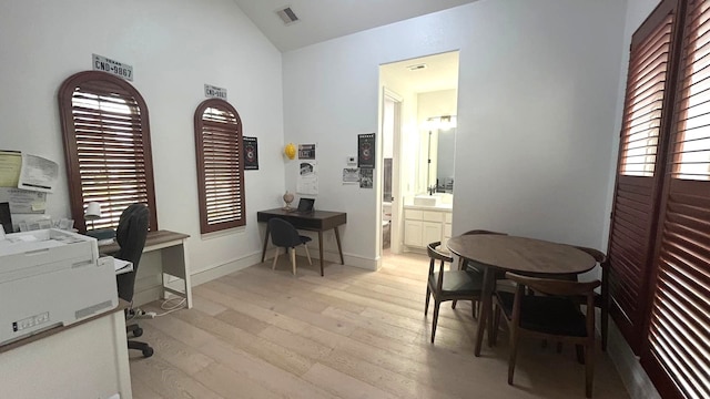 home office featuring lofted ceiling, light wood finished floors, visible vents, and baseboards