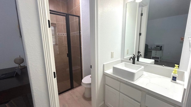 full bathroom with wood finished floors, a stall shower, vanity, and toilet