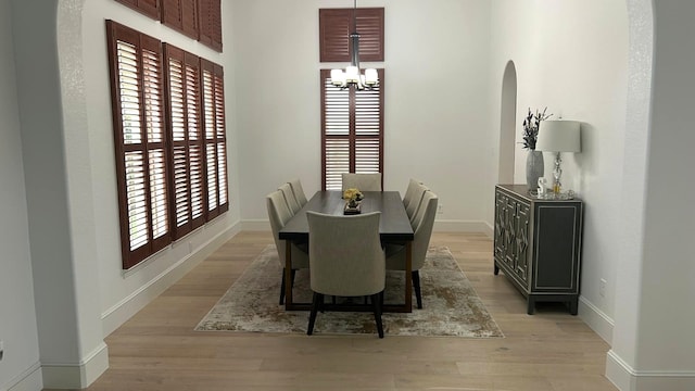 dining room featuring light wood-style floors, a notable chandelier, and baseboards