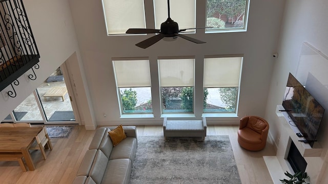 living room with light wood finished floors, a towering ceiling, and a healthy amount of sunlight