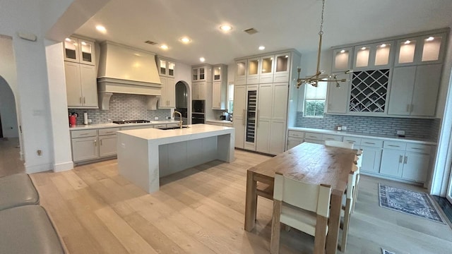 kitchen with arched walkways, light countertops, and glass insert cabinets