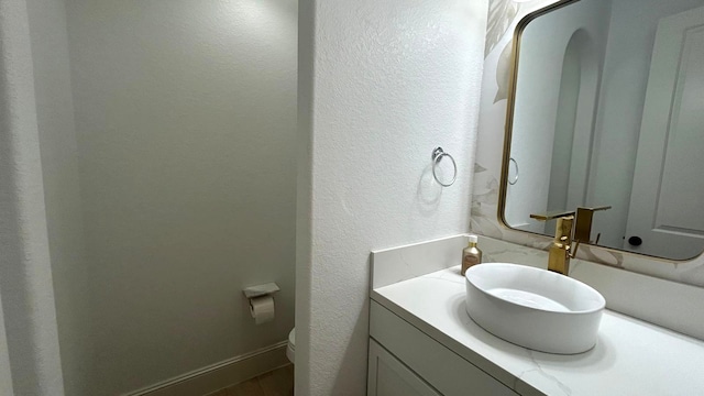 bathroom with a textured wall, vanity, and toilet