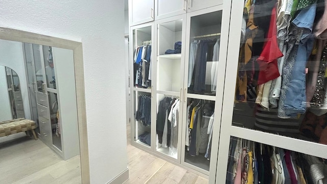 spacious closet featuring arched walkways and light wood-style flooring