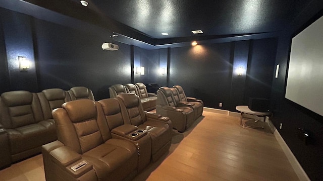 home theater with light wood-style floors, visible vents, and baseboards