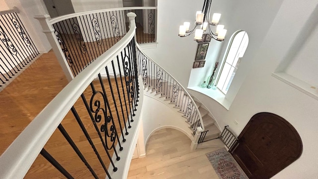 stairs featuring a chandelier, a high ceiling, and wood finished floors