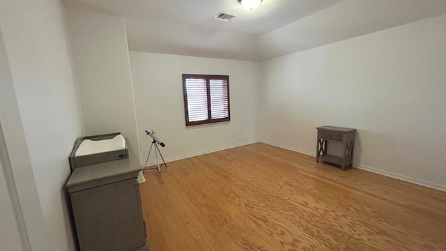 spare room featuring visible vents, baseboards, and wood finished floors