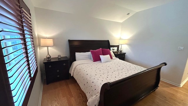 bedroom with baseboards, vaulted ceiling, and wood finished floors