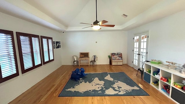 exercise room with visible vents, a raised ceiling, wood finished floors, and french doors