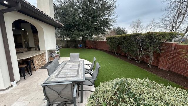 view of yard featuring outdoor dry bar, outdoor dining area, a patio area, and a fenced backyard