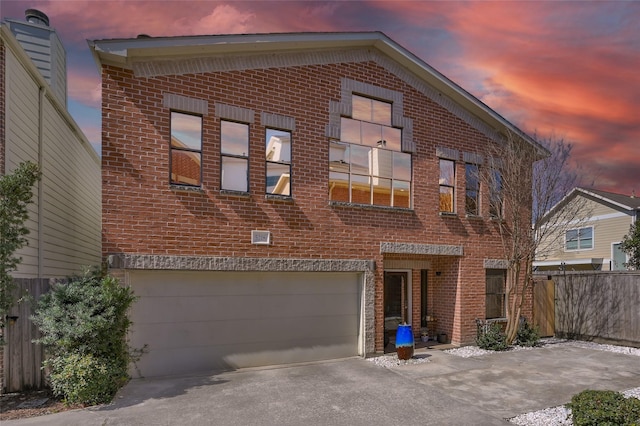 view of front of home with a garage, fence, concrete driveway, and brick siding