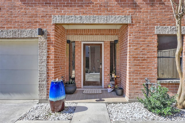 view of exterior entry with a garage and brick siding