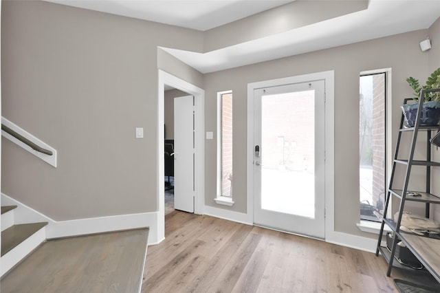 foyer entrance featuring light wood finished floors, stairs, and baseboards