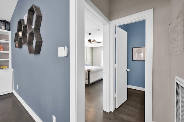 hall with dark wood-style flooring and baseboards