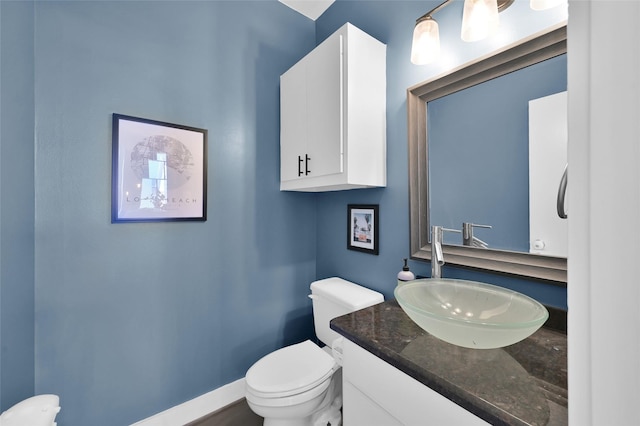 bathroom featuring baseboards, vanity, and toilet